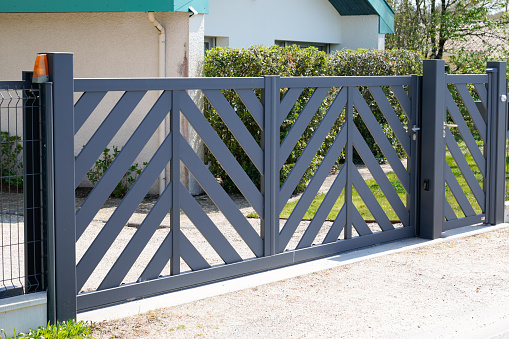 A modern panel fence in anthracite color, a visible sliding gate to the garage and a wicket with a letterbox.