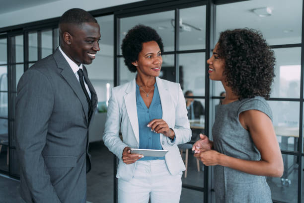 Business people in the office. Shot of three coworkers having a discussion in modern office. Successful business team in meeting using digital tablet and discussing business strategy. Confident business people working together in the office. Corporate business persons discussing new project and sharing ideas in the workplace. african american stock pictures, royalty-free photos & images