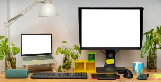 istock Blank white computer monitors on light wooden table with keyboard, mockup. Contemporary office and laptop 1454530747