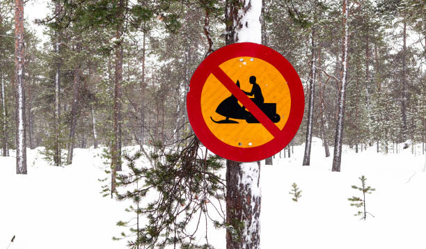 School crossing sign in a snowy mountainous village guides drivers for safety. Rural road with houses and snowcapped hills. Winter travel in remote areas.
