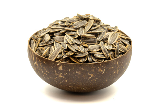Shelled sunflower seeds isolated on white background. Salted sunflower seeds in a coconut bowl. close up