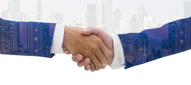 Businessmen shaking hands against the backdrop of the blue sky and buildings on fine day. Closeup of business people shaking hands over a deal
