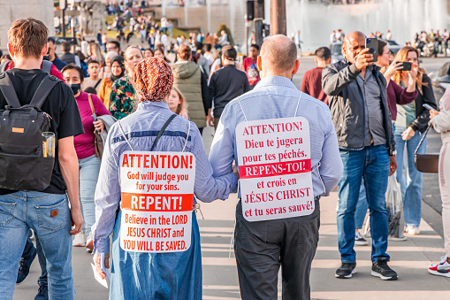 Couple of religious fanatics walking in a street in Paris and carrying signs asking to repent of our sins in France