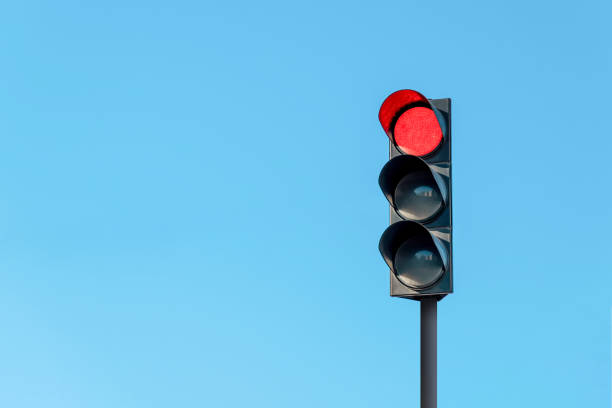 Modern traffic light with red light in front of cloudless sunny blue sky Modern traffic light with red light in front of cloudless sunny blue sky red light stock pictures, royalty-free photos & images