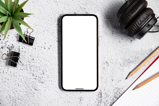 top view of smartphone with blank screen on white stone office desktop