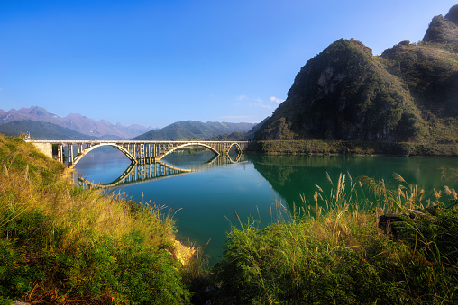 A view of the lake with the bridge and rocks in the background in Guangxi, China