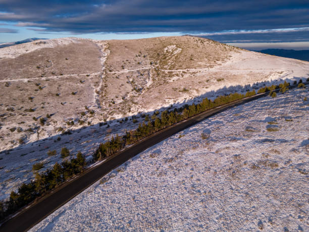 montañas cubiertas de nieve al atardecer con un camino sinuoso en primer plano vista aérea - road winding road mountain spiral staircase fotografías e imágenes de stock