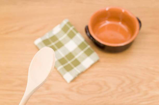 natural terracotta bowl and wood kitchen utensils and a table napkin on a wooden background with copy space