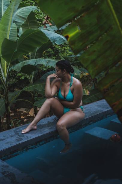 istock Vertical shot of a beautiful hispanic bikini model posing on the pool side 1454542065