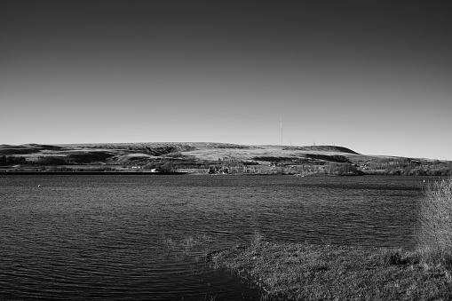 A grayscale of a Delph Reservoir looking across to Winter hill TV transmitter station in Lancashire