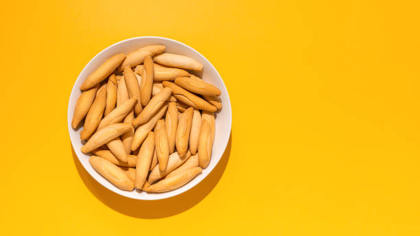 Top view of Spanish mini picos on yellow Top view of picos - bread sticks in the bowl on the yellow background with hard shadow and copy space breadstick stock pictures, royalty-free photos & images