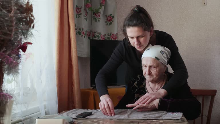 The woman helps her grandmother cut her nails.