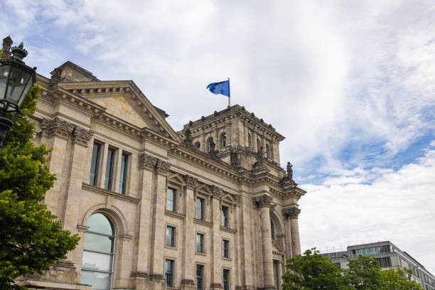 el edificio del reichstag, sede del parlamento alemán, el bundestag. la bandera europea en un asta de bandera en el techo. el reichstag es el signo de la unidad alemana. - berlin germany the reichstag german culture contemporary fotografías e imágenes de stock