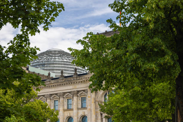 la cúpula del reichstag, sede del bundestag alemán, a través de los árboles del tiergarten. la cúpula se ha convertido en una de las atracciones más visitadas y un hito de berlín - berlin germany the reichstag german culture contemporary fotografías e imágenes de stock