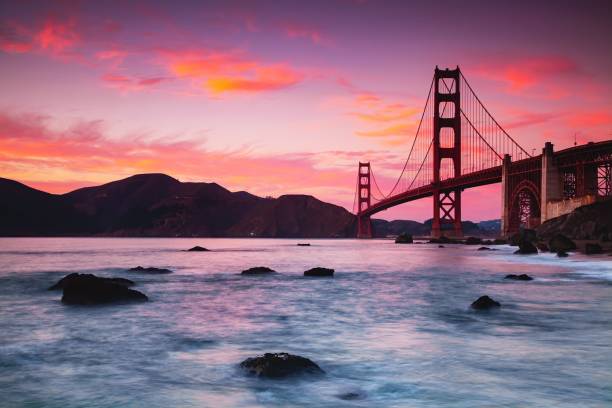 belle vue sur le golden gate bridge à travers l’eau au coucher du soleil violet, san francisco, états-unis - san francisco bay area golden gate bridge night bridge photos et images de collection