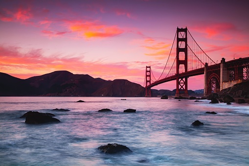 A beautiful view of the Golden Gate Bridge across the water at purple sunset, San Francisco, USA