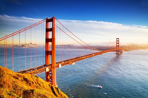 A perspective shot of The Golden Gate Bridge in the background of the cityscape, San Francisco.