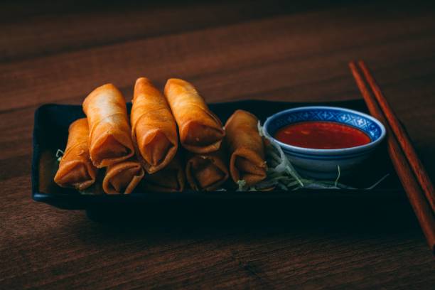 istock Close-up shot of deep-fried spring rolls served with separate sauce and chopsticks 1454551882