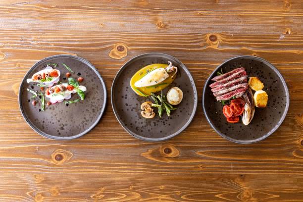 Top view of three different meals on circular plates on the wooden table