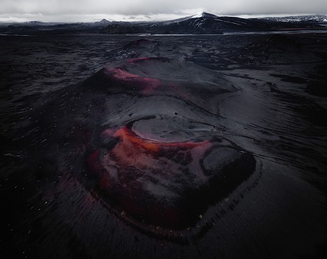 A night view of volcano and hot red lava flowing on its slopes