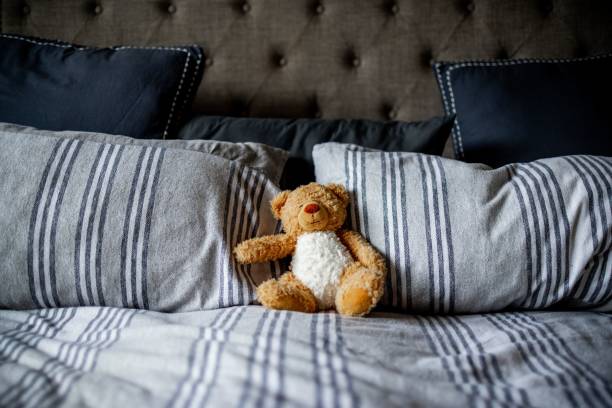 istock View of a teddy bear on a bed with striped blue and white pillows 1454554570