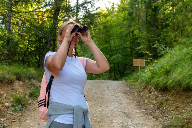 istock Female hiker with binoculars on a trail in a dense forest 1454555847