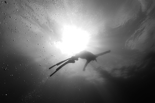 A silhouette of freediver coming back to the surface