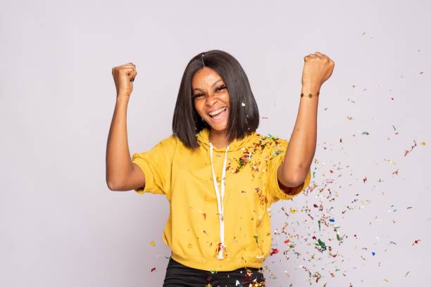 istock Nigerian excited black lady celebrating with spread confetti 1454561233
