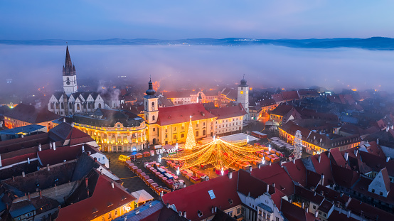Sibiu, Romania. Foggy amazing morning view, drone flight, with main square and Christmas Market, medieval downtown of Transylvania.