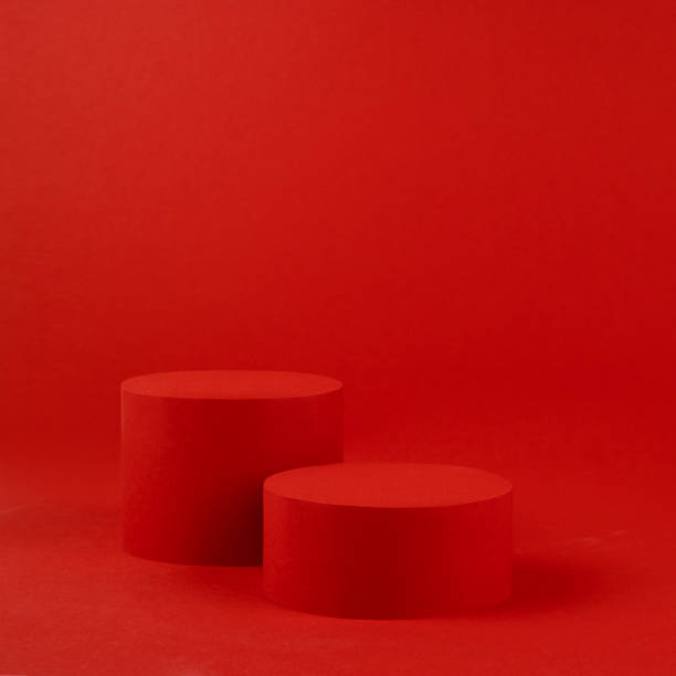 istock Two red cylinder podiums mockup on table on rich saturated background for presentation cosmetic products, gifts, goods in minimal modern style, copy space, square. Template for advertising, design. 1454563286