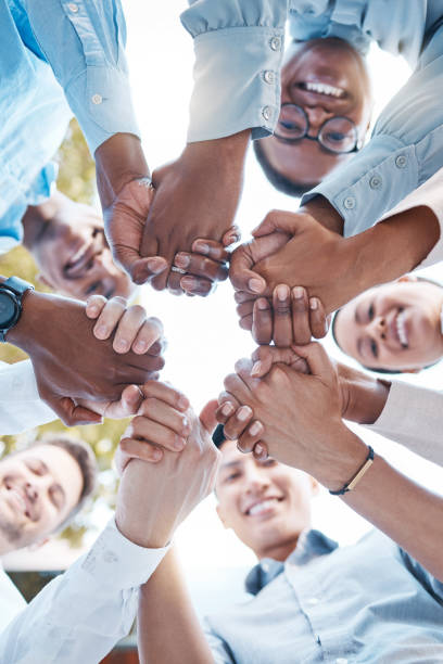 istock Low angle, business people and holding hands in support circle, community partnership or team building motivation. Smile, happy or teamwork diversity in trust, collaboration or growth mission success 1454563555