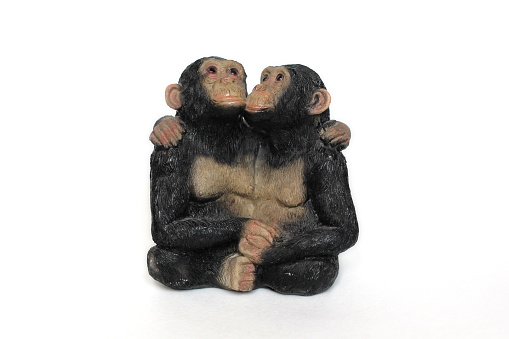 antique statuette of cuddling monkeys on a white background