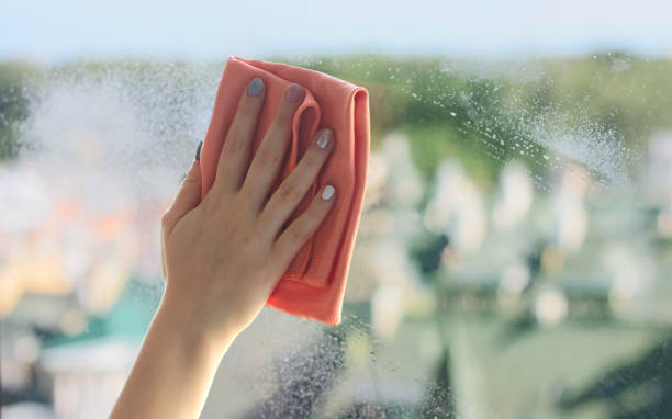 female hand with a rag washes a window