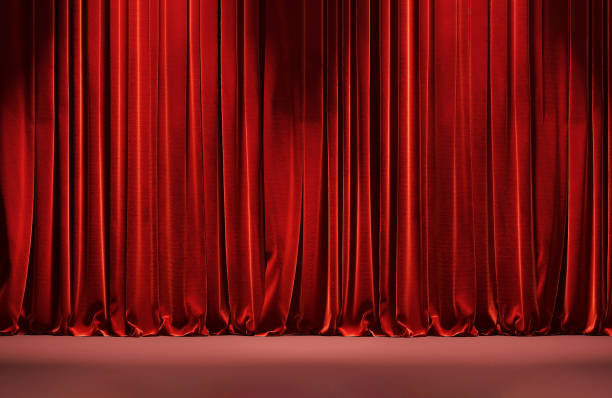 istock Closed vibrant red satin curtain drapes on maroon red stage floor with spotlight from top ceiling 1454570323