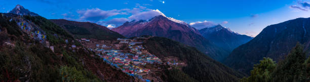 Namche Bazaar illuminated by moonlight below Himalayan mountain peaks panorama stock photo