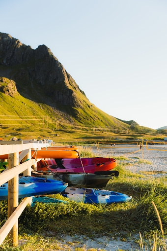 A view of the colorful water sport things at the beach camping site with green mountain view during the Midnight Sun