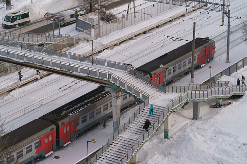 Moscow oblast, Russia - february 14, 2021: Fabrichnaya station. Public transport in the Moscow Region. Railway. Red and grey colored electric train motion. Cold winter day. View from above.
