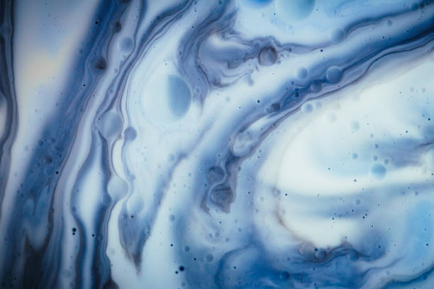 Macro close up depicting the abstract forms and shapes in a mixture of blue and orange paint and oil.
