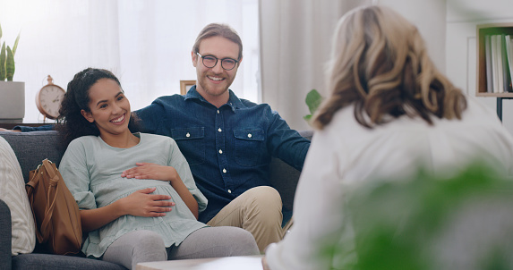 Pregnant, happy and couple in counseling with a psychologist consulting, listening and helping. Communication, pregnancy and healthy woman talking to a marriage therapist with partner for support