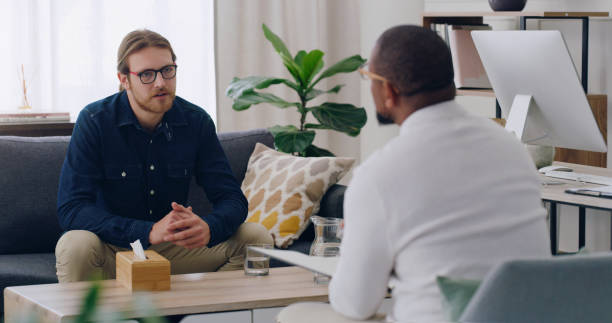 homem, paciente ou conversando com psicólogo no sofá em terapia de aconselhamento de saúde mental, depressão ou ansiedade. psicologia, estresse ou terapia de aconselhamento de bem-estar ajuda para a pessoa na clínica de reabilitação - psychiatrists couch - fotografias e filmes do acervo