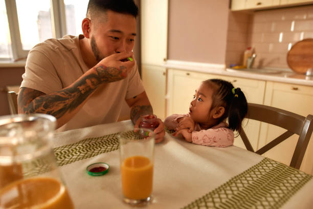 azjatycka dziewczynka patrząc na ojca jedzą jedzenie dla niemowląt - sparse healthy eating single father contemporary zdjęcia i obrazy z banku zdjęć