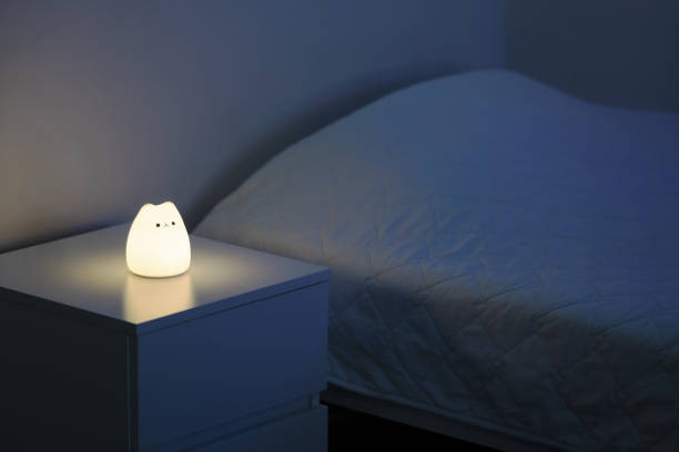 istock Cute cat shaped night lamp standing on a bedside table next to bed. 1454584069