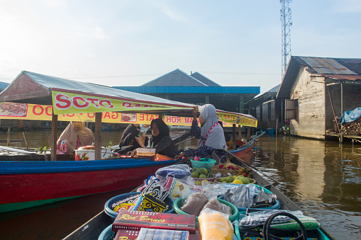 Banjarmasin, Kalimantan - Indonesia – 04 November 2022: everyday in the morning, women in floating market lok baintan, Banjarmasin city, Indonesia paddled their boat to carry out buying and selling various basic needs such as vegetables and crops from villages along martapura river.
