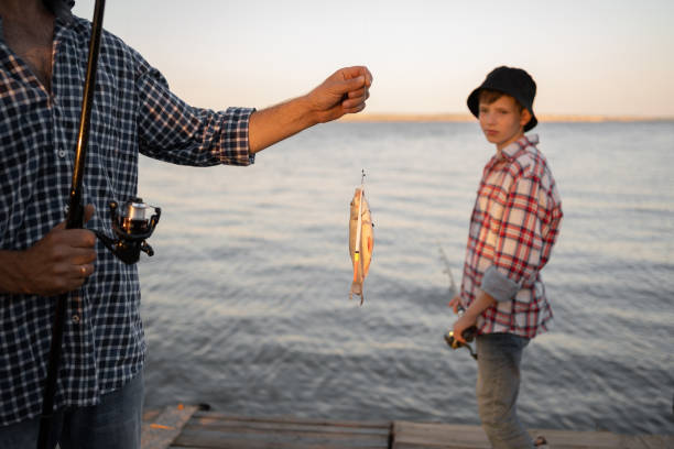 Man caught a fish boy son in the background. copy space