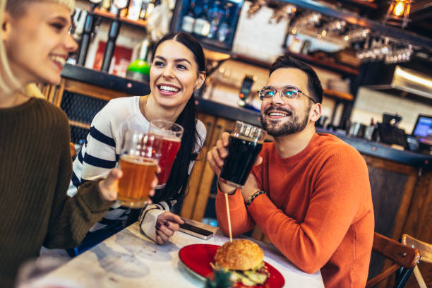 istock Smiling young friends drinking craft beer in pub 1454585195