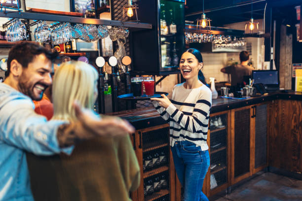 istock Young female waitress or bartender serving drinks in a bar carrying a tray with beer 1454585317