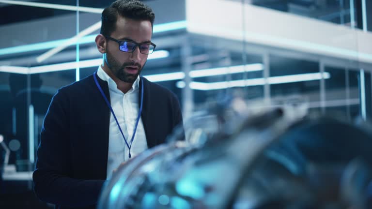 Smart Chief Engineer in Glasses Explaining the Advanced Technology of a Modern Innovative Industrial Invention to a Team of College Students on an University Course.