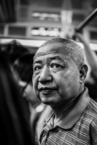 Shanghai, China – February 12, 2018: A vertical grayscale portrait of a Chinese man standing in bus