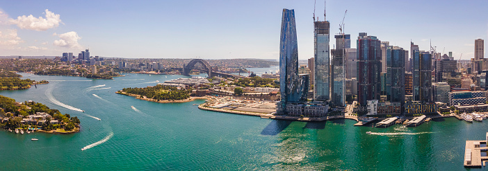 Panoramic aerial drone view of Barangaroo waterfront precinct in Sydney City, NSW showing Barangaroo Reserve and the Harbour Bridge on a sunny day