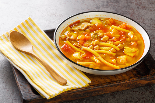 Canarian soup with meat, pasta, chickpeas and vegetables close-up on a plate on the table. horizontal